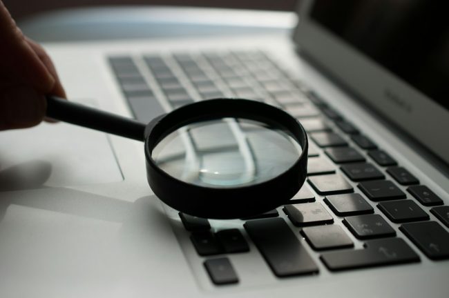 Documentación del AI Act evidencias y revisión Lupa sobre un portátil, representando la revisión de la documentación y las evidencias que exige el AI Act a una empresa